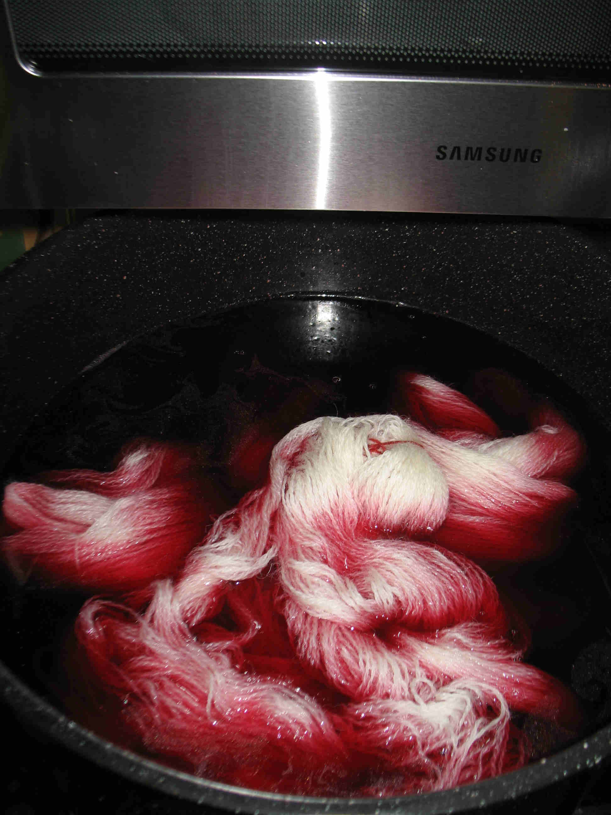 Putting wet wool yarn into dye pot.jpg