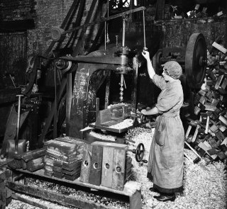 Woman_operating_boring_machine;_boring_wooden_reels_for_winding_barbed_wire.png