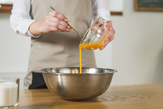 mid-section-woman-pouring-egg-yolk-stainless-steel-bowl-wooden-table_23-2148028017.jpg