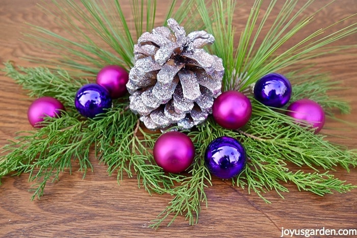 Close-up-of-a-silver-pink-glittered-pine-cone-decoration-adorned-with-hot-pink-purple-balls-fresh-evergreen-branches-_new.jpg